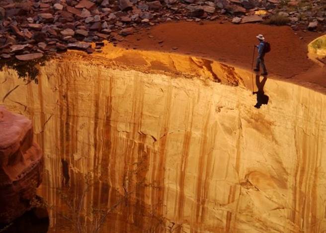 游客走在美国犹他州格兰峡谷河边的倒影，看似是如临万丈深渊